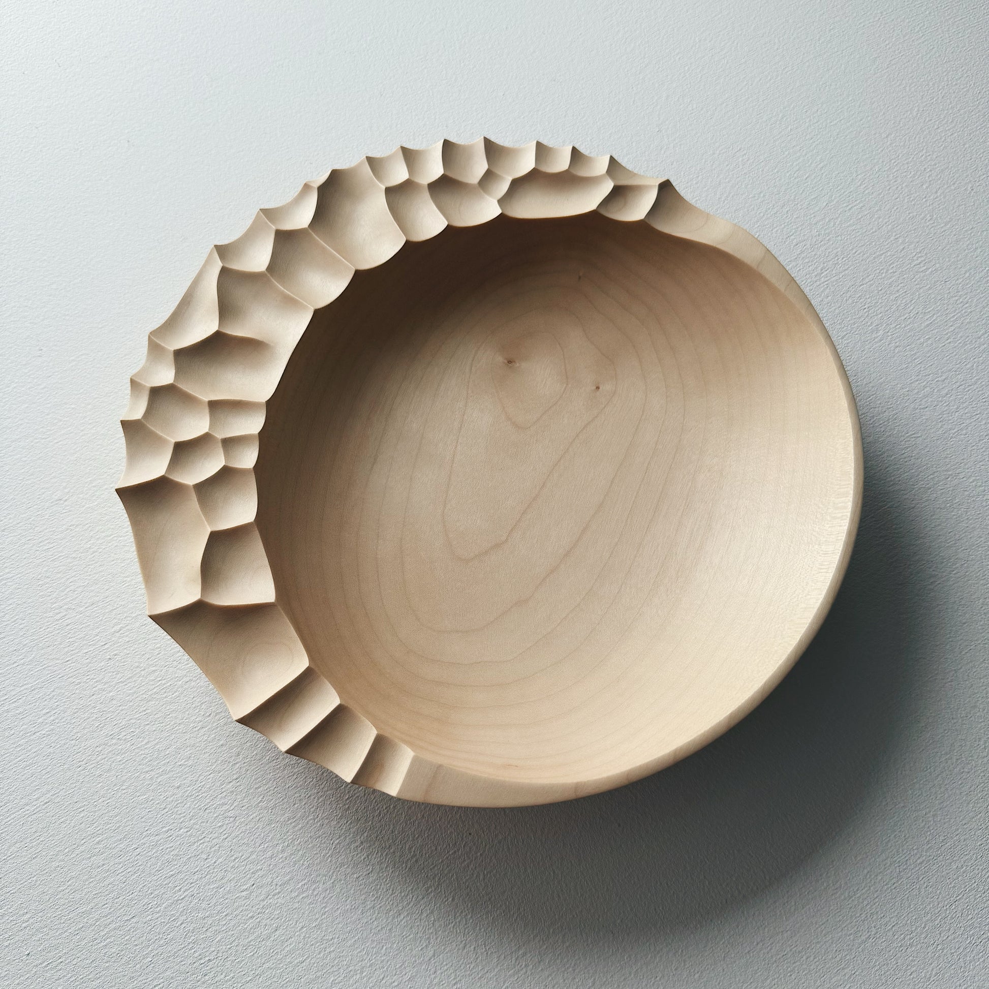 Wooden bowl with sculptural pattern on a white background