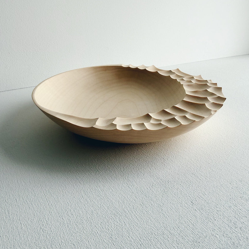 Wooden bowl with sculptural pattern on a white background