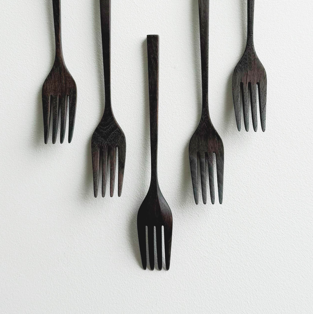 Set of five black walnut forks on a white background