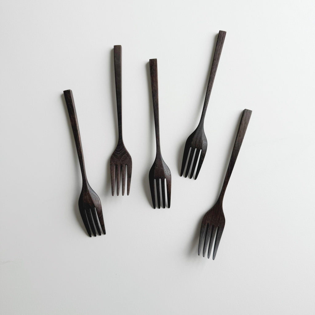Set of five black walnut forks on a white background
