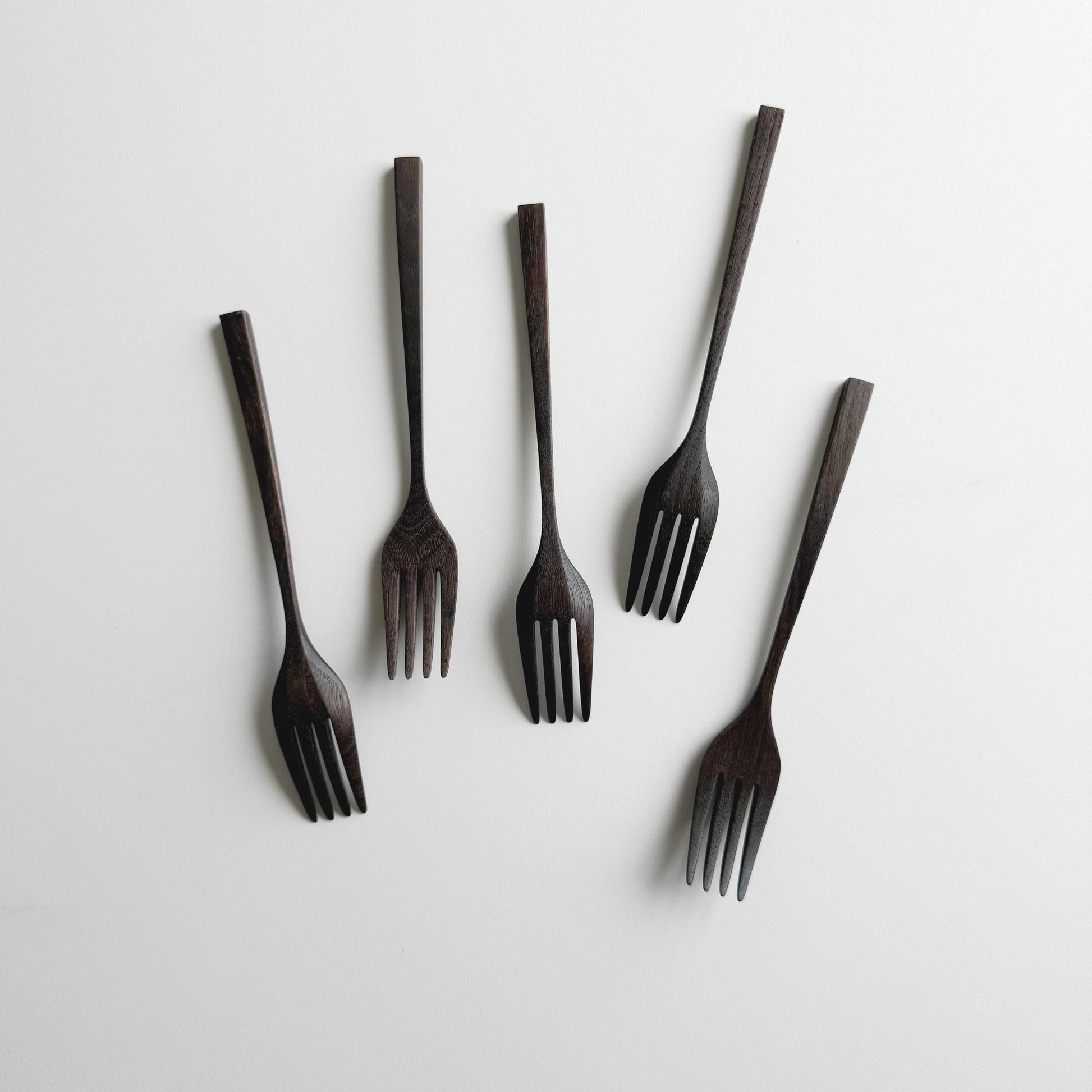 Set of five black walnut forks on a white background
