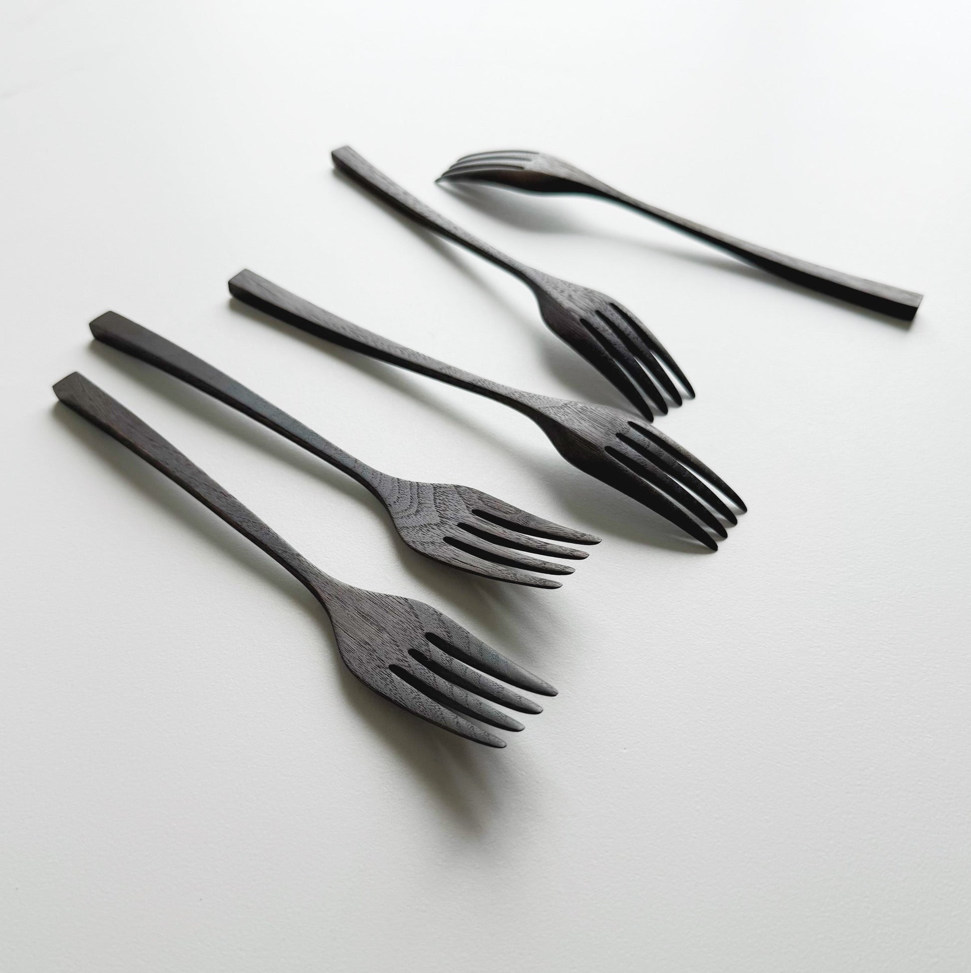 Set of five black walnut forks on a white background
