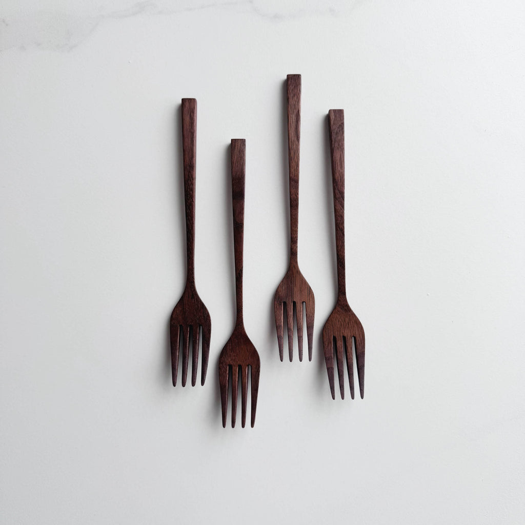 Set of five walnut wooden forks on a white background