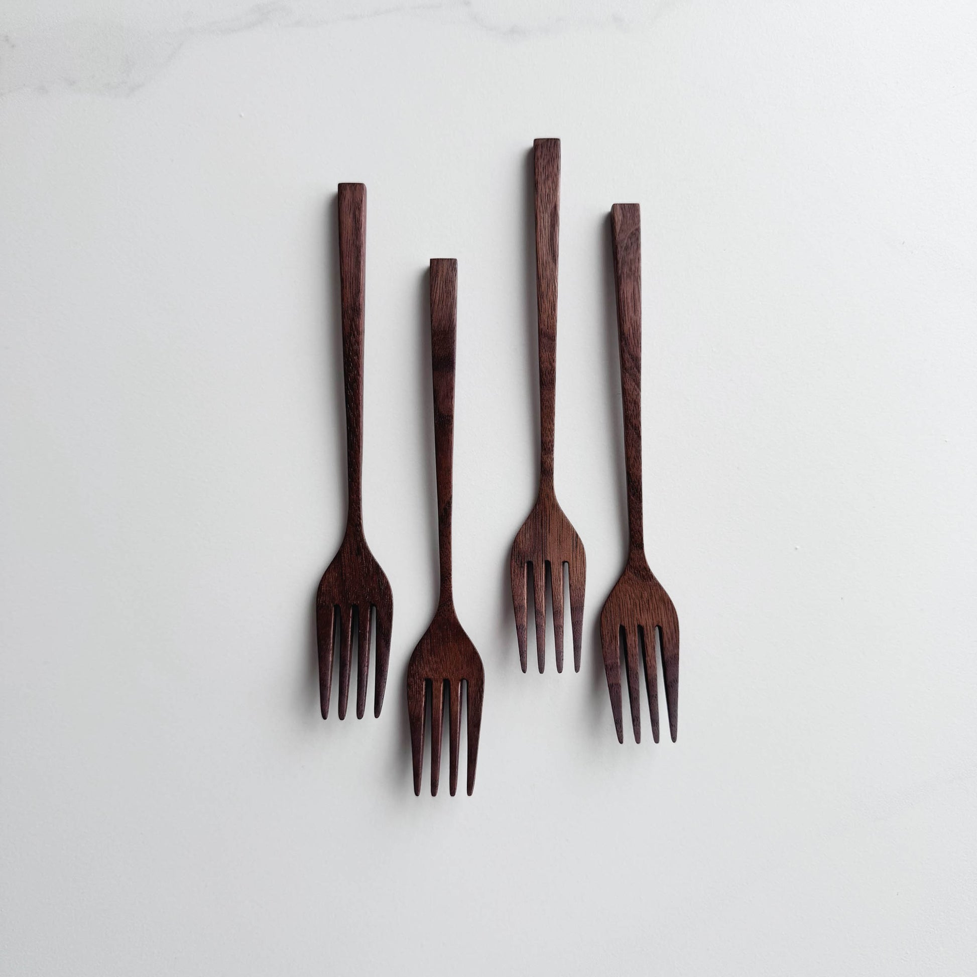 Set of five walnut wooden forks on a white background