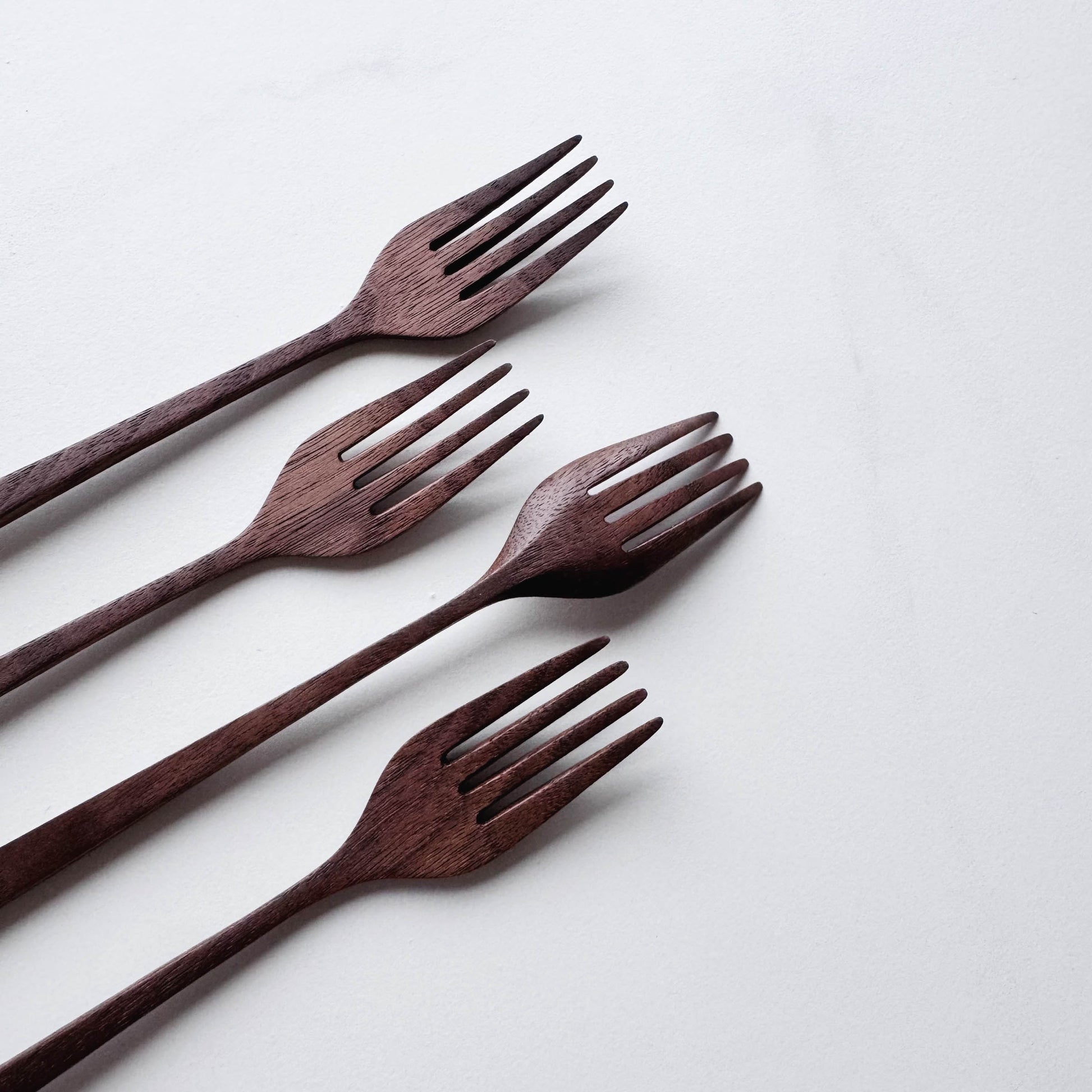 Set of four walnut wooden forks on a white background
