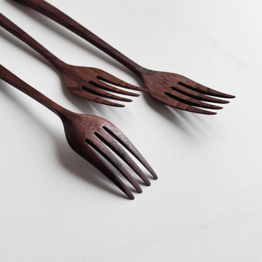 Set of three walnut wooden forks on a white background
