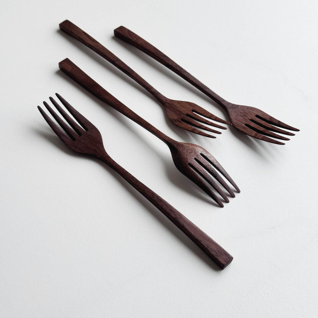 Set of four walnut wooden forks on a white background
