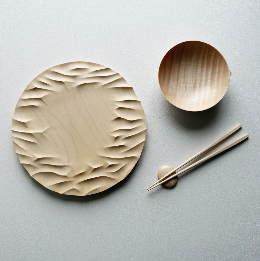 Large Gathered sycamore wooden plate with textured edge and bowl with chopsticks on a light background