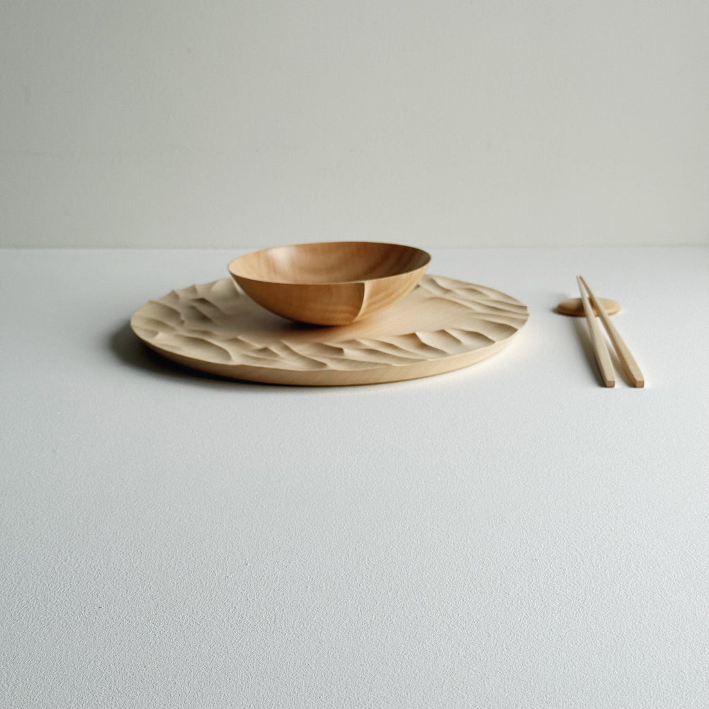 Large Gathered sycamore wooden plate with textured edge and bowl with chopsticks on a light background