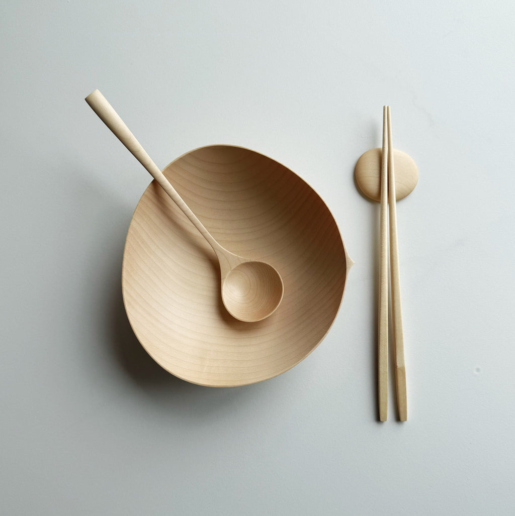 Sycamore oval bowl, angled eating spoon, wooden chopsticks and pebble rests on a white background

