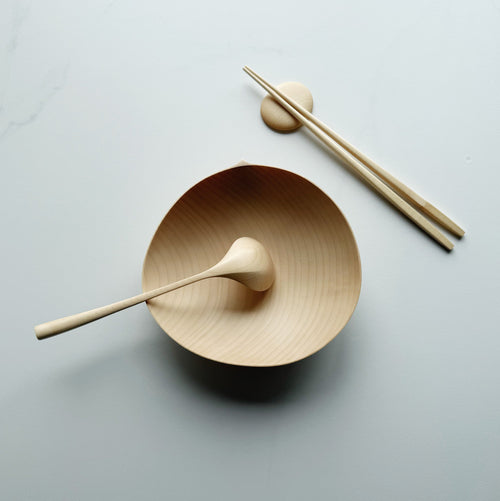 Sycamore oval bowl, angled eating spoon, wooden chopsticks and pebble rests on a white background
