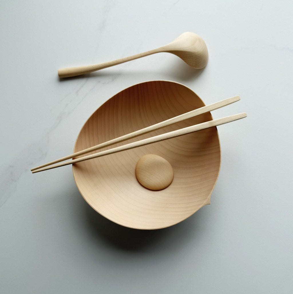 Sycamore oval bowl, angled eating spoon, wooden chopsticks and pebble rests on a white background
