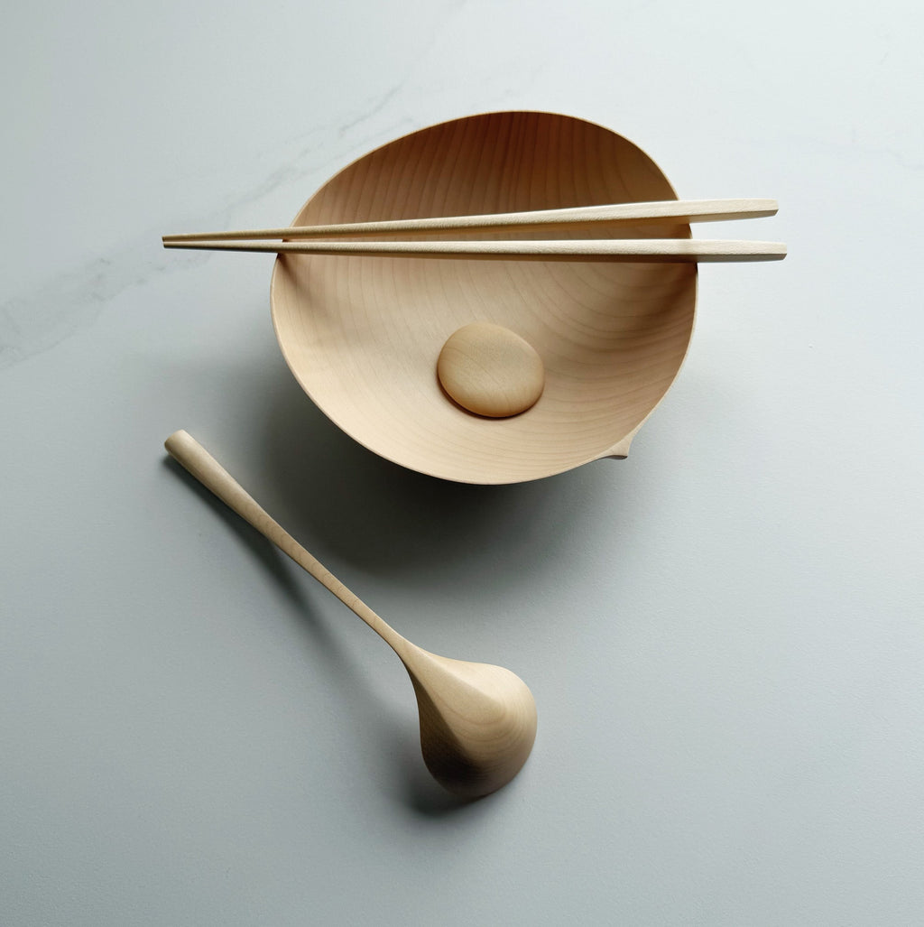 Sycamore oval bowl, angled eating spoon, wooden chopsticks and pebble rests on a white background

