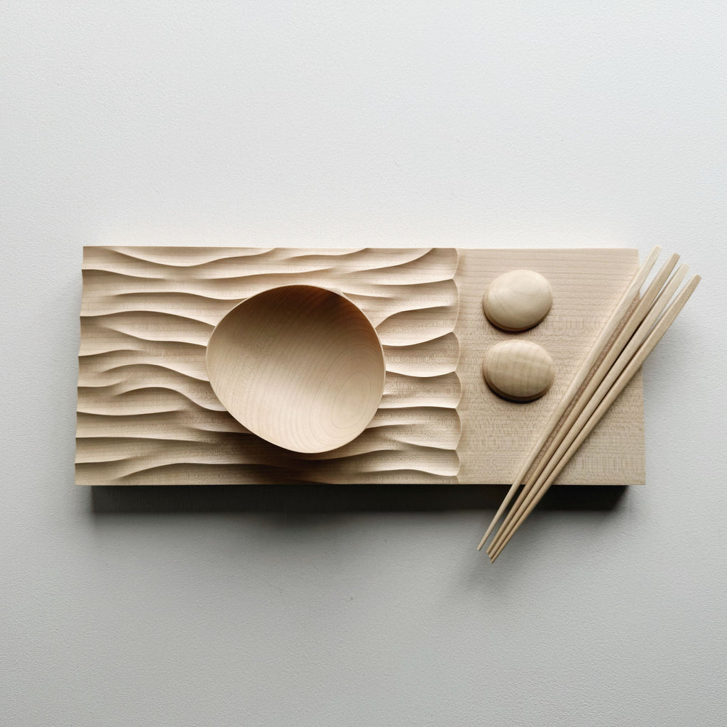 Making Waves sycamore board, with oval bowl, chopsticks and pebble rests in sycamore on a light background.