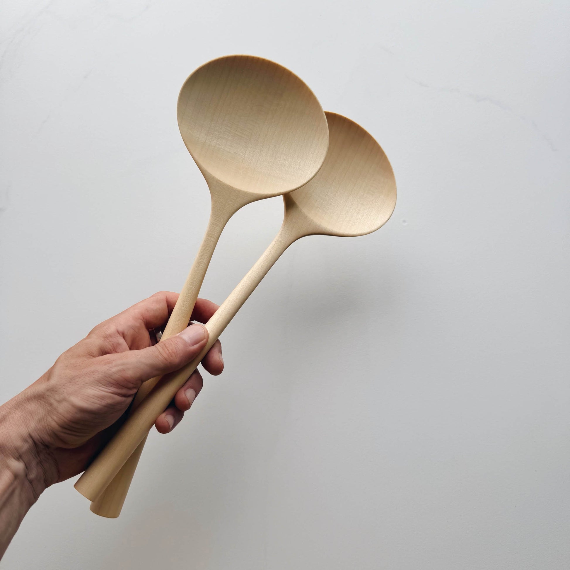 Hand holding two large oval servers against a plain background