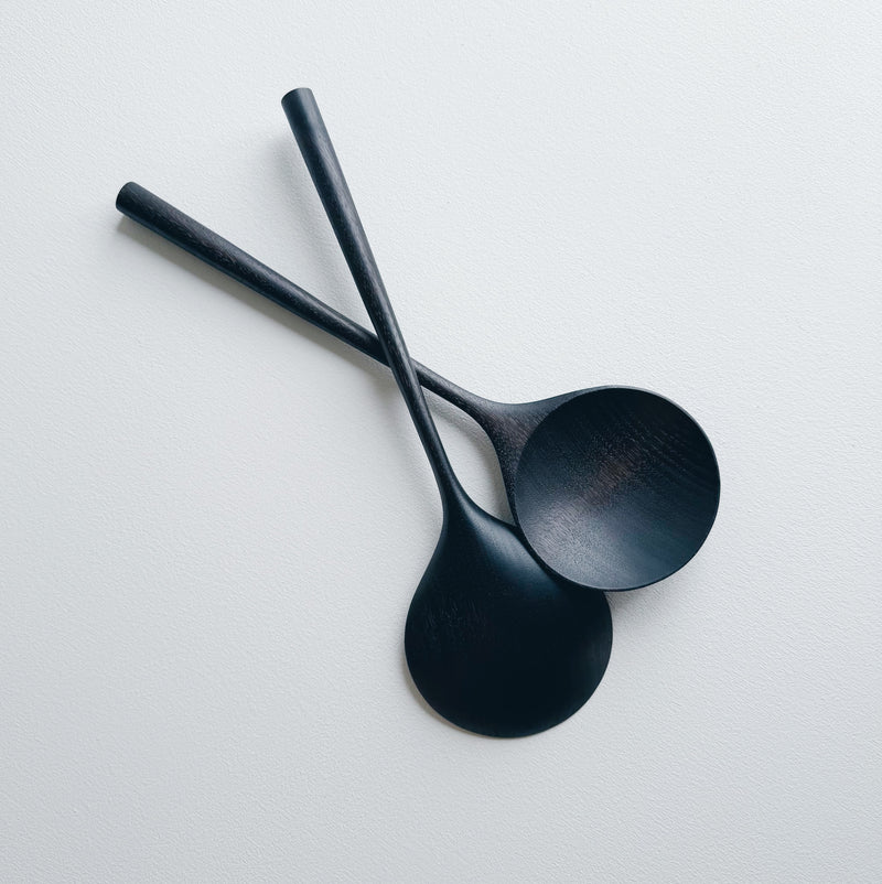 Two ebonised walnut serving spoons on a white background