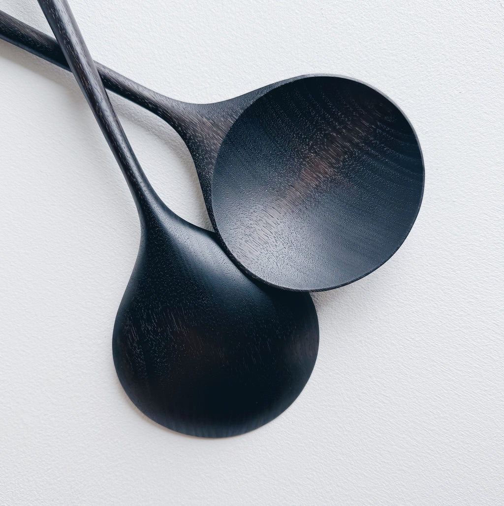 Two ebonised walnut serving spoons on a white background
