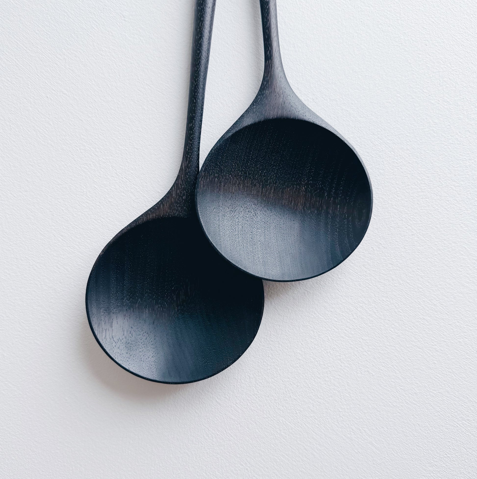 Two ebonised walnut serving spoons on a white background