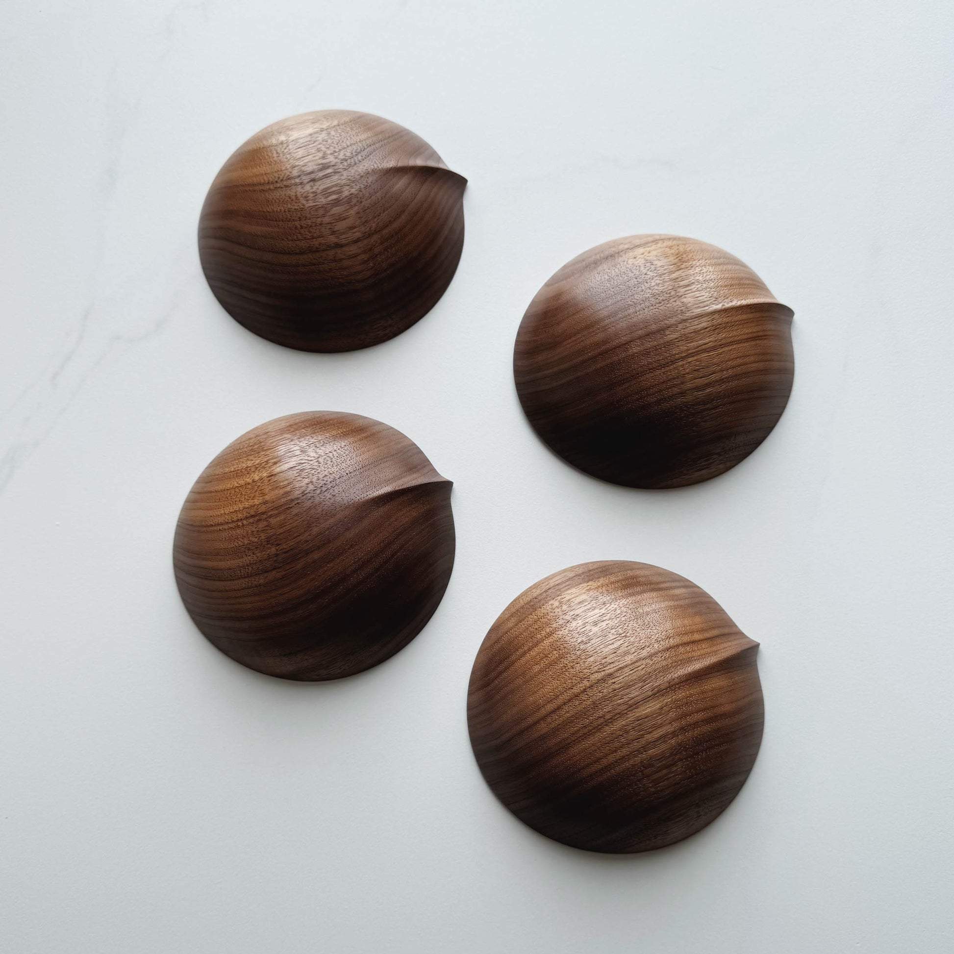 Four wooden bowls in walnut on a white background