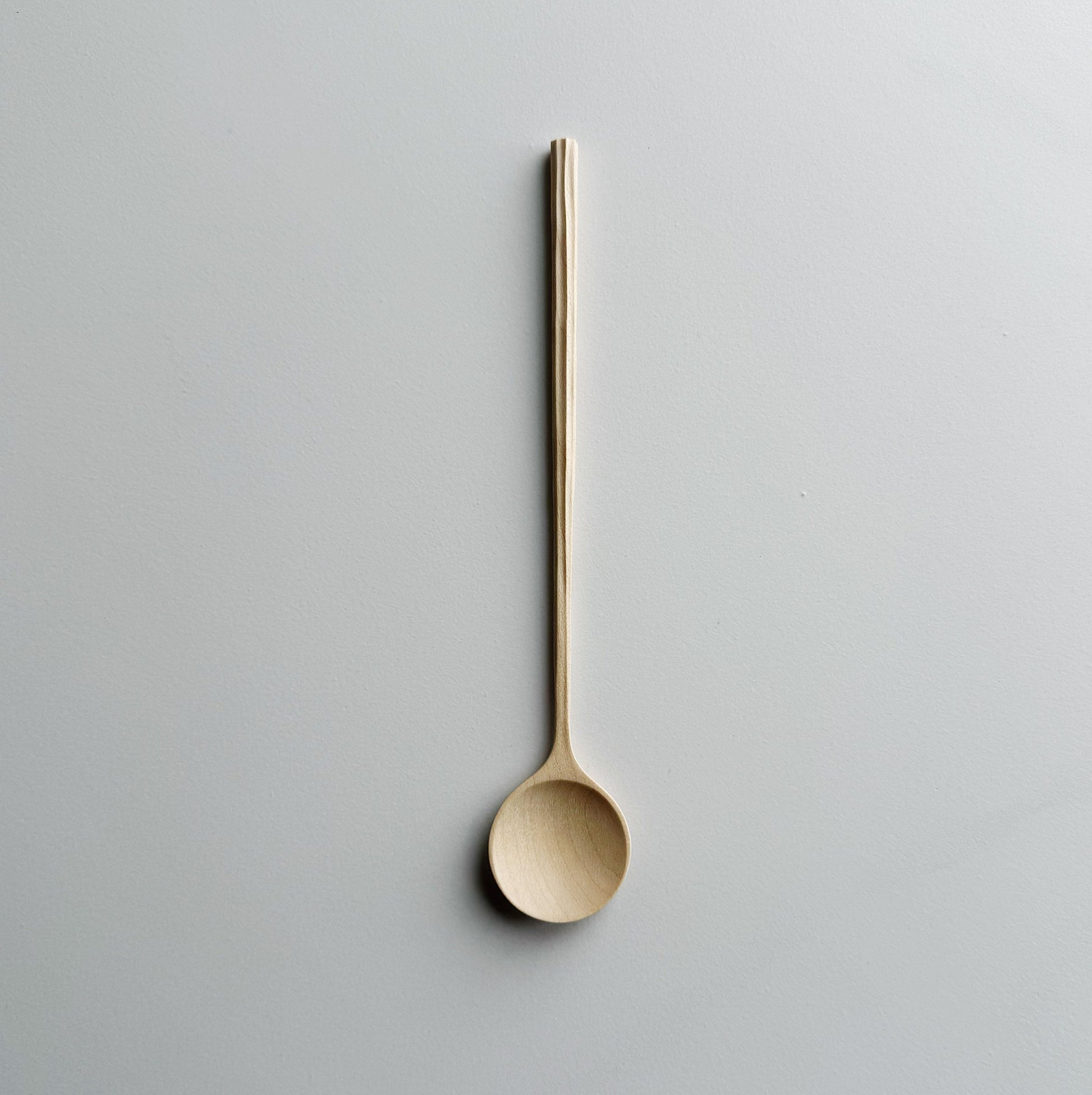 Sycamore spoon with sculpted handle on a light background
