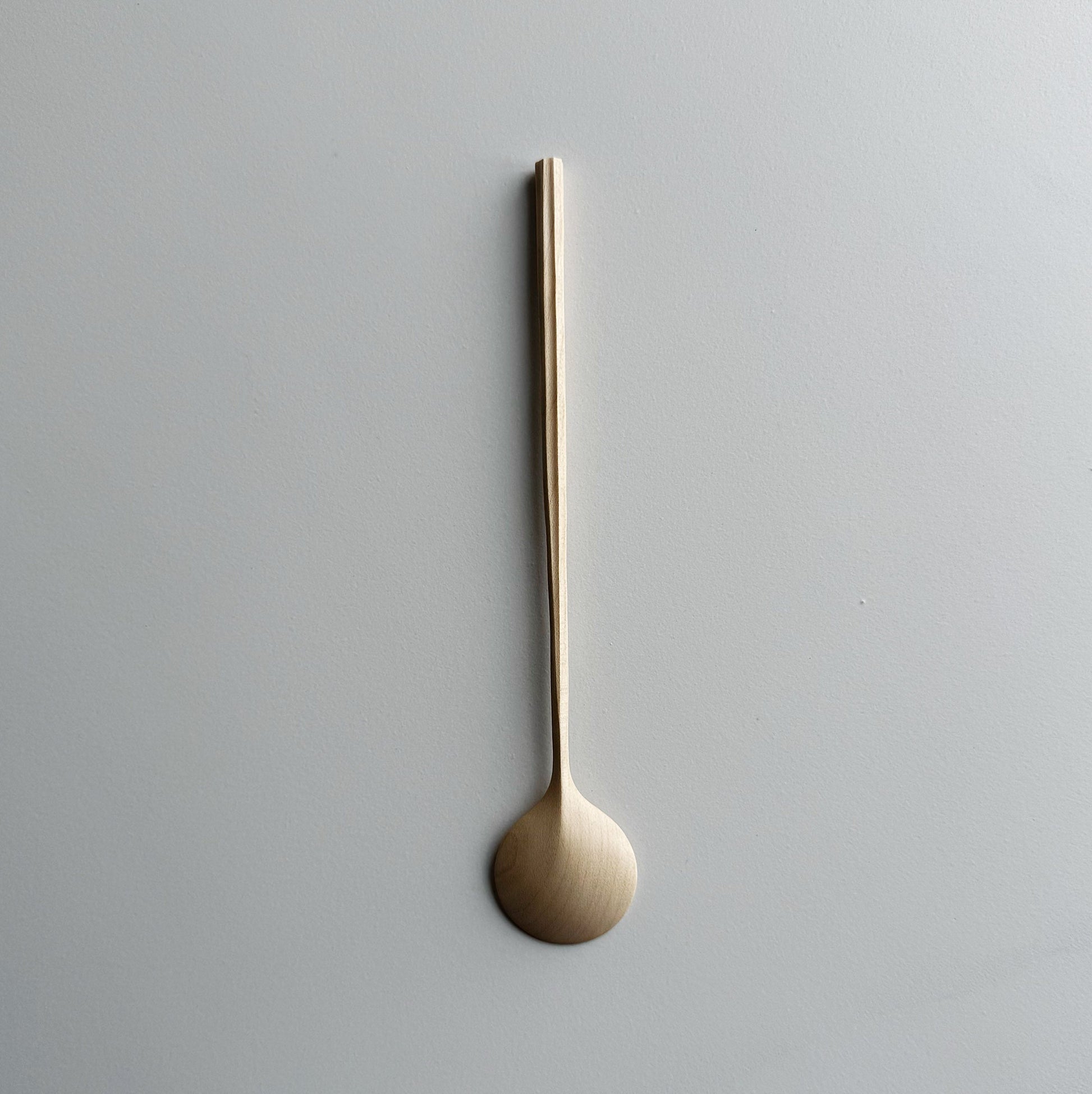 Sycamore spoon with sculpted handle on a light background
