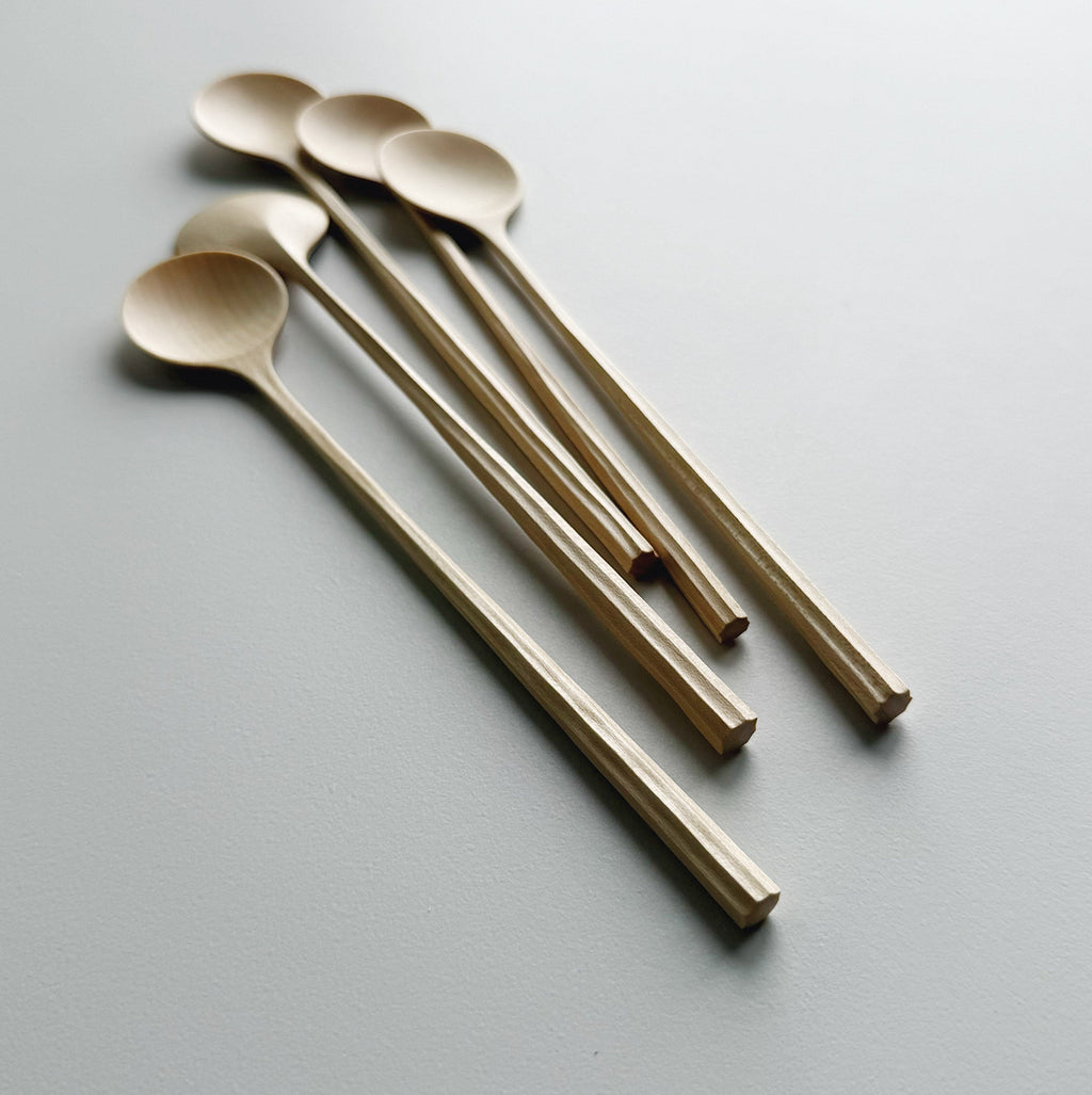 Five sycamore spoons with sculpted handles on a light background
