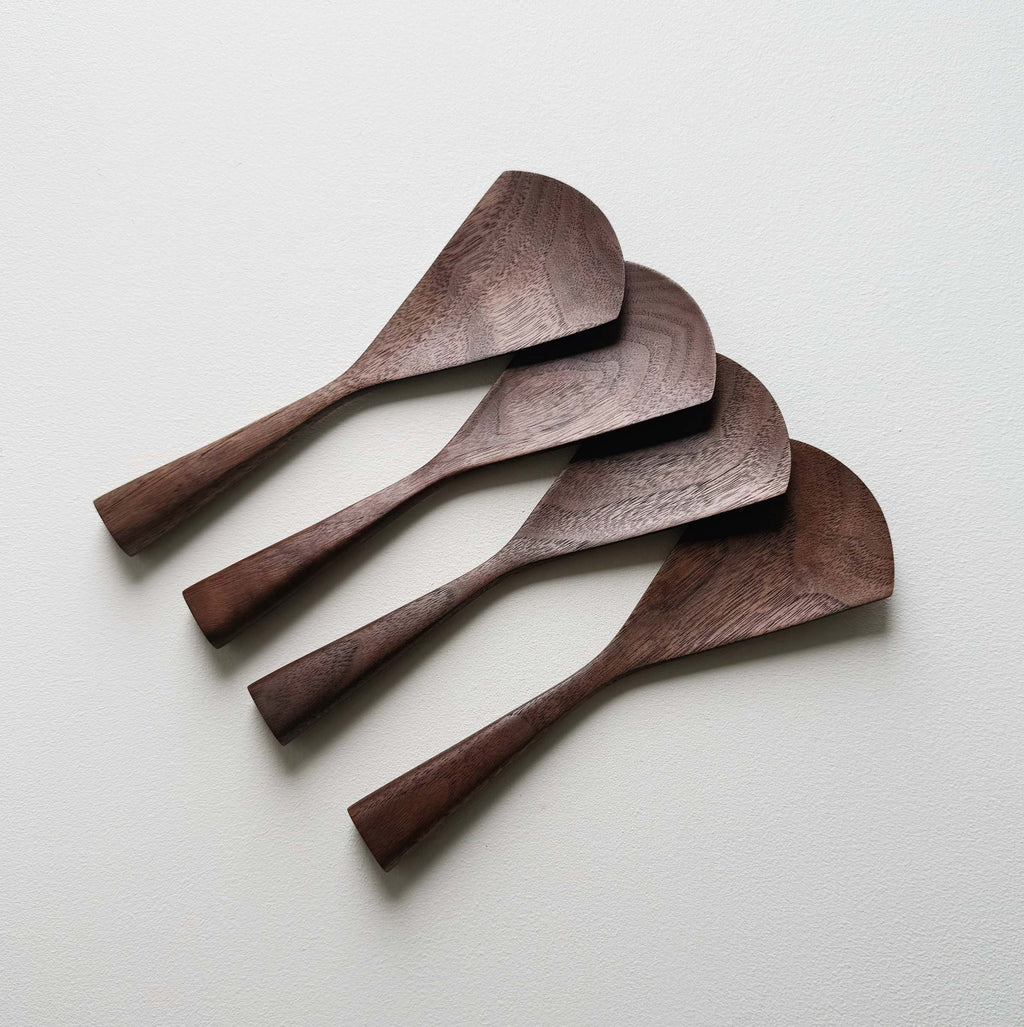 Set of four walnut serving paddles on a light background