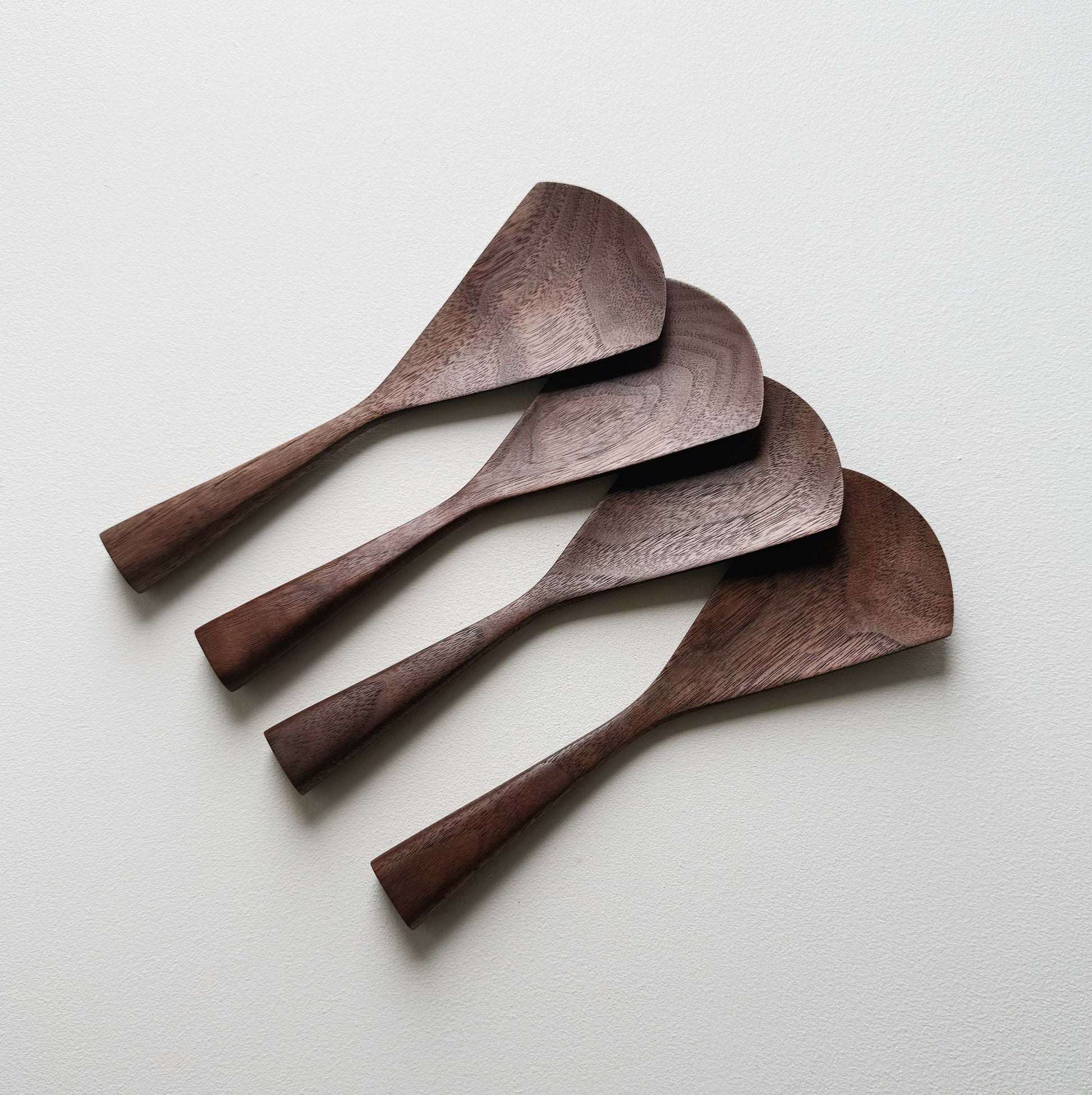 Set of four walnut serving paddles on a light background