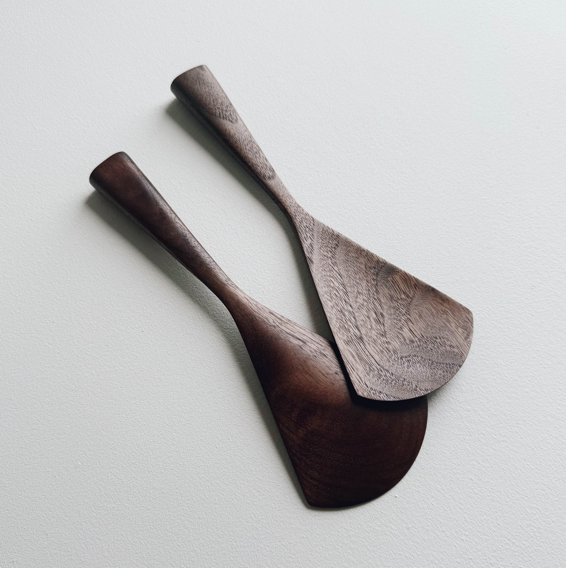 Two walnut serving paddles on a light background
