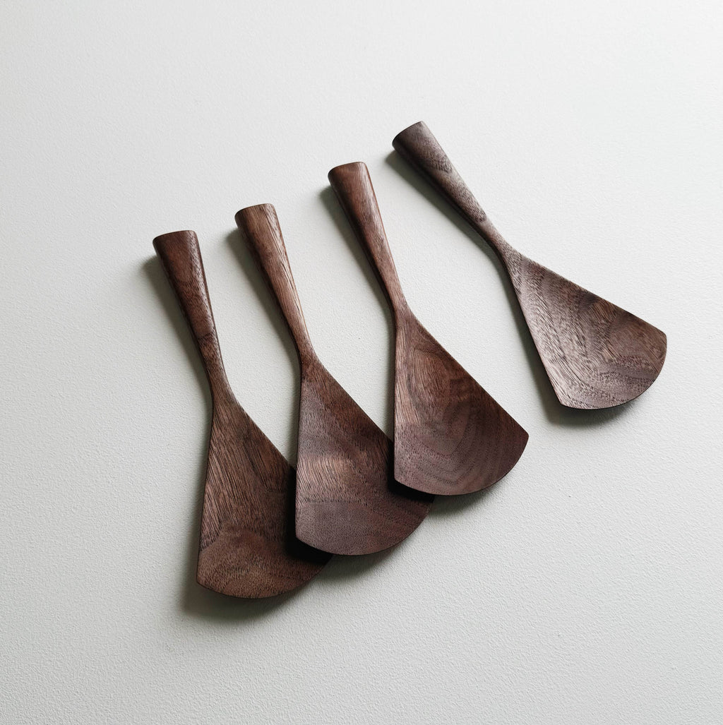 Set of four walnut serving paddles on a light background
