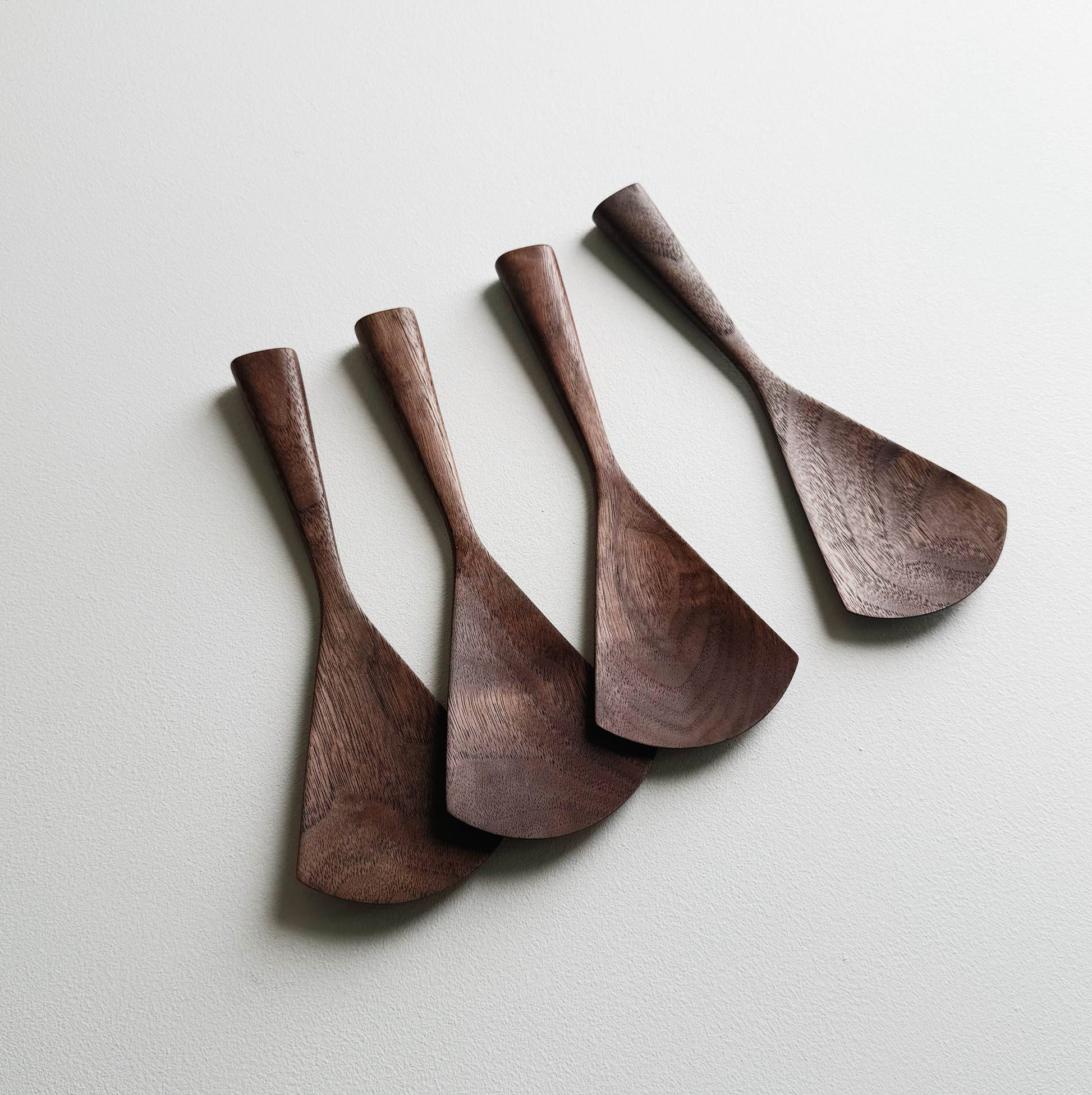 Set of four walnut serving paddles on a light background
