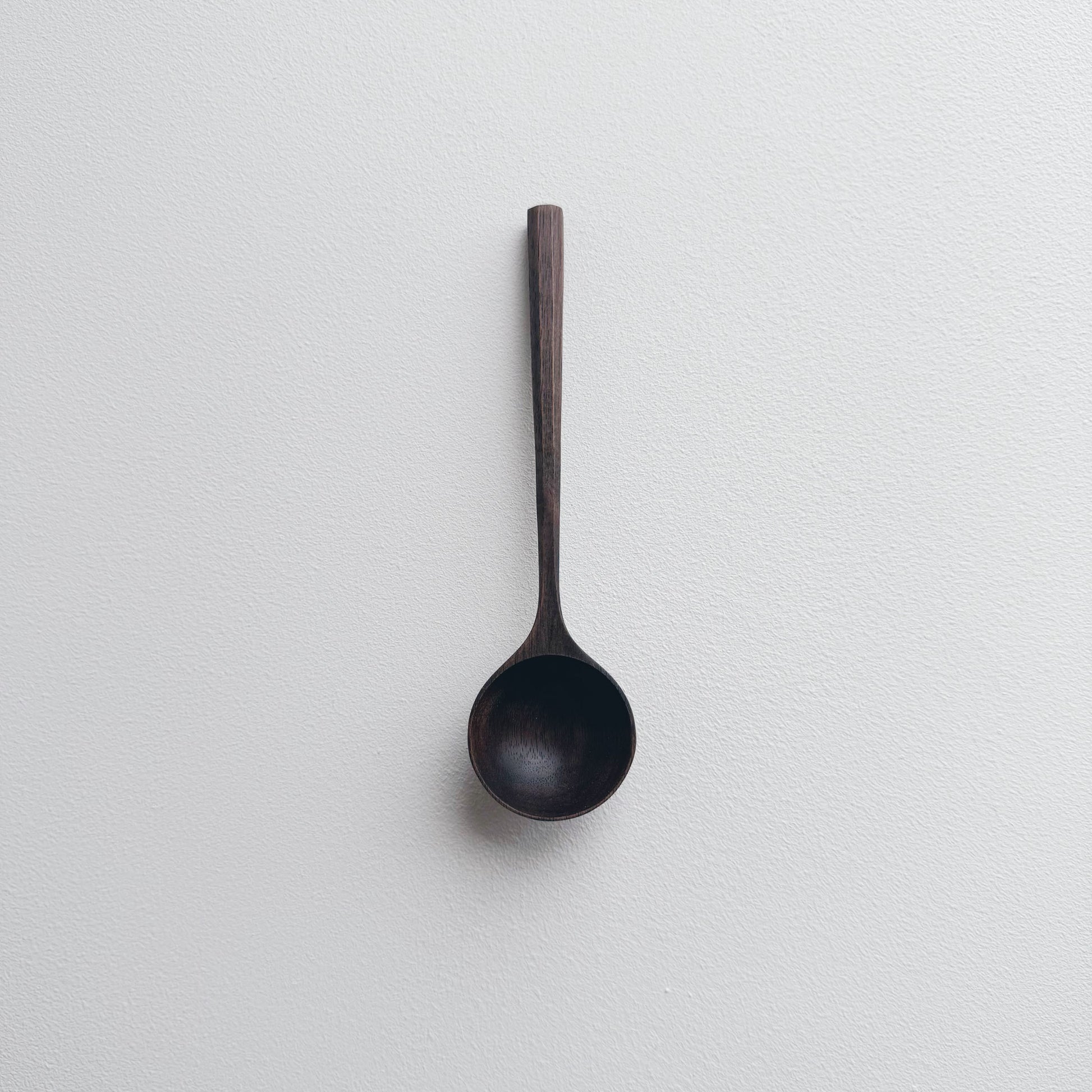 Black walnut wooden scoop on a white background