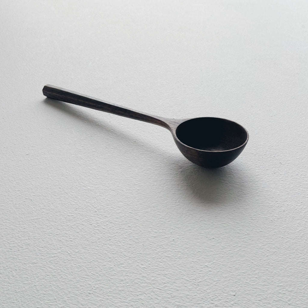 Black walnut wooden scoop on a white background
