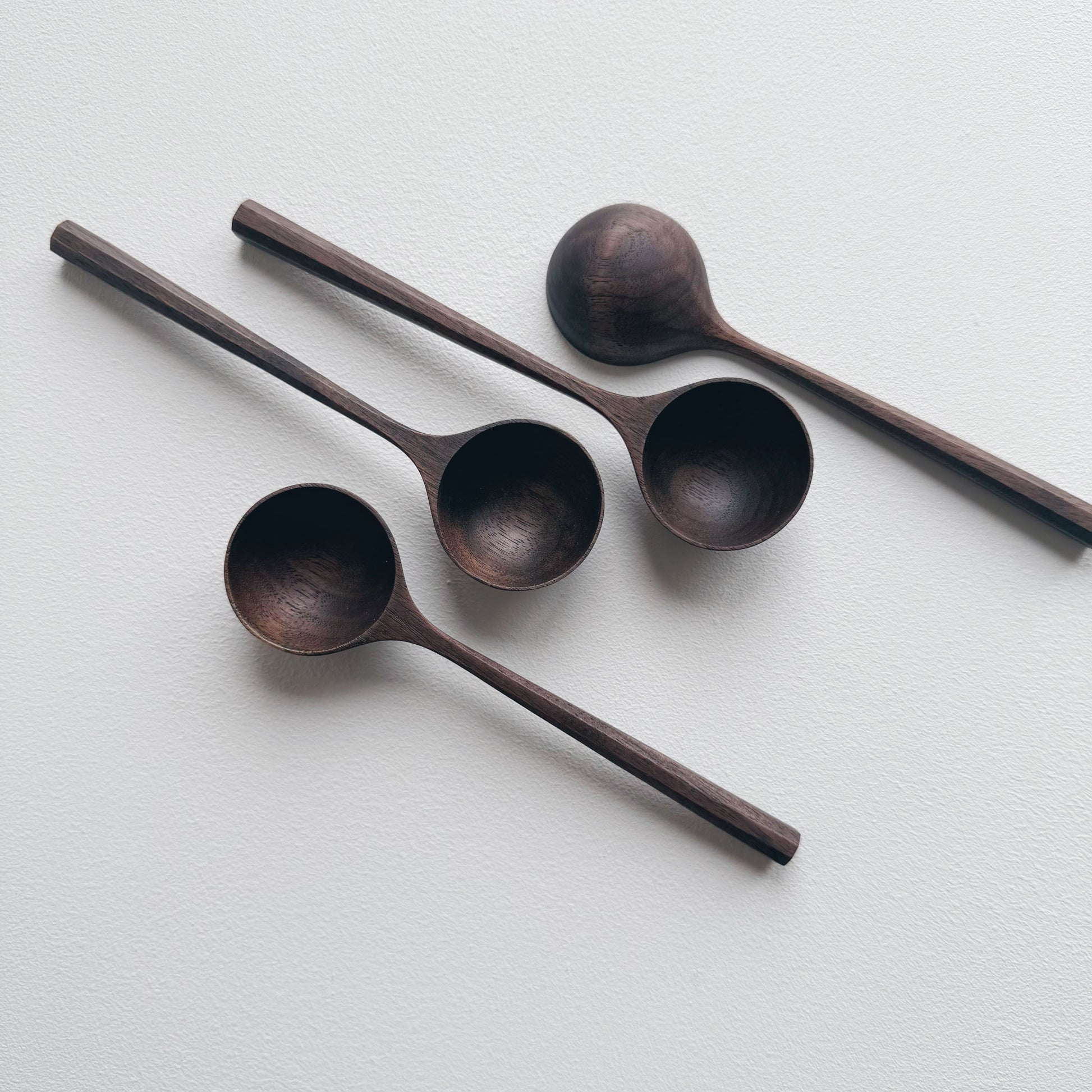 A set of black walnut wooden scoops on a white background

