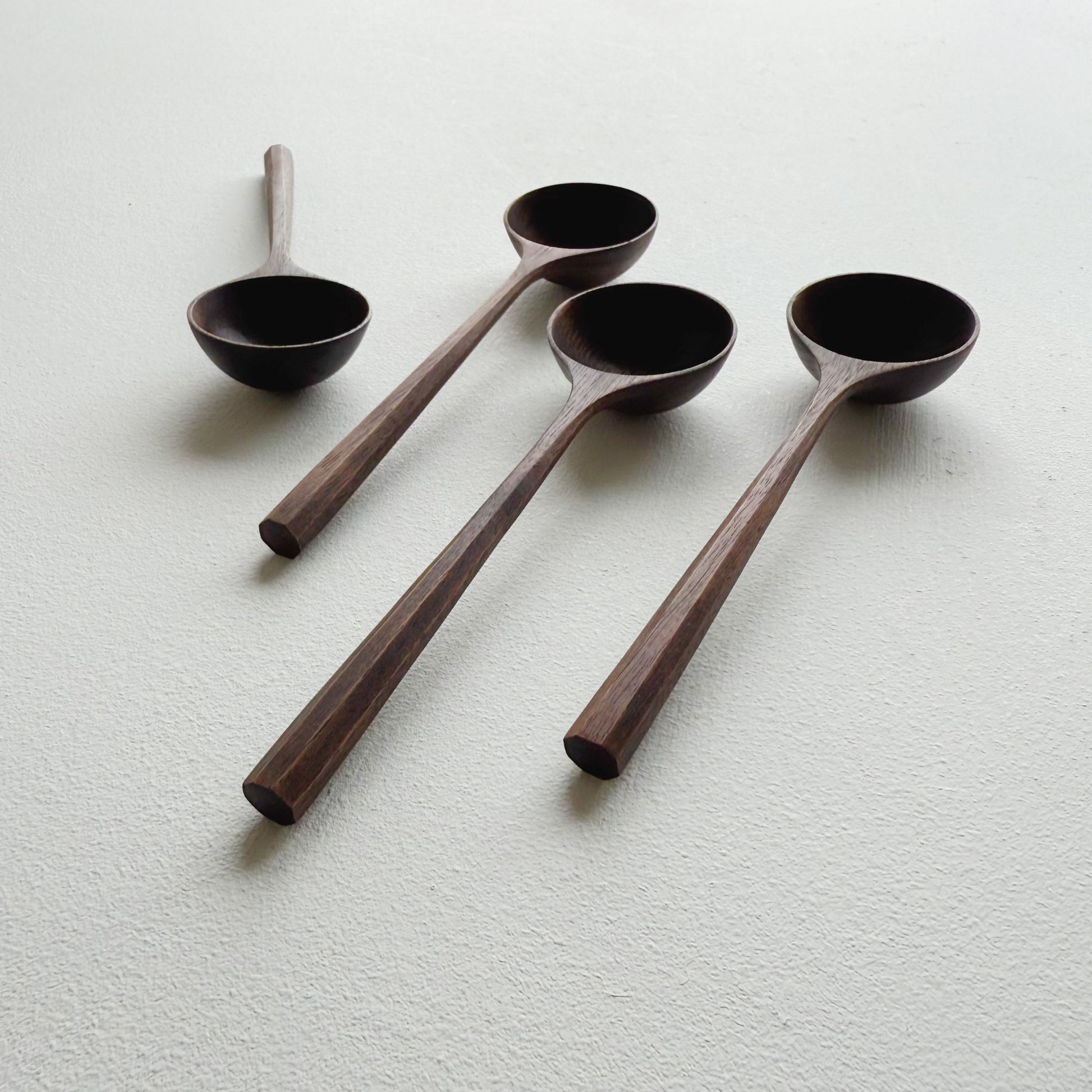 A set of black walnut wooden scoops on a white background
