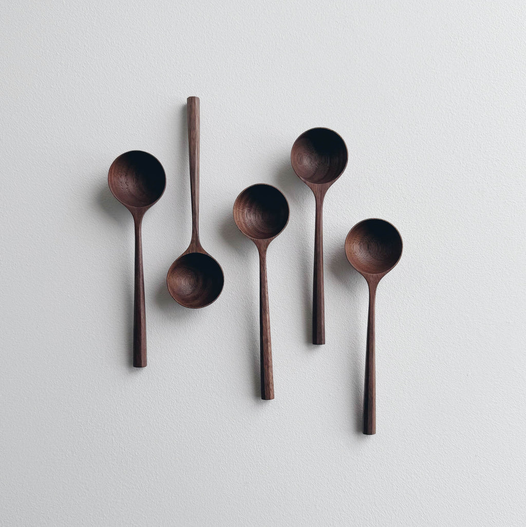 Set of five walnut wood scoops on a white background
