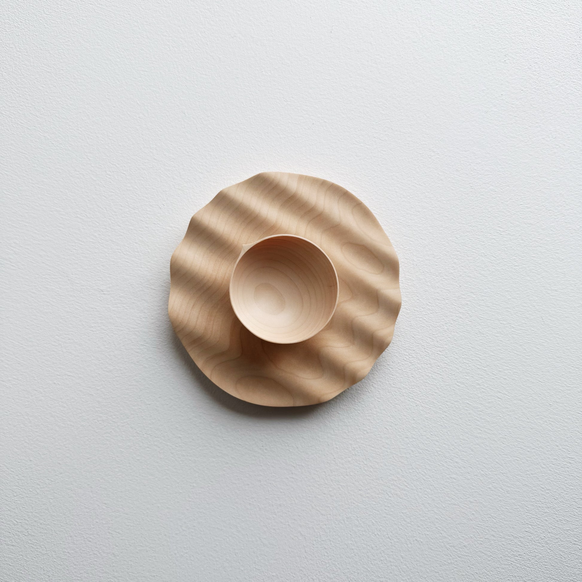 Sycamore bowl placed on a sycamore wavy plate on a white background