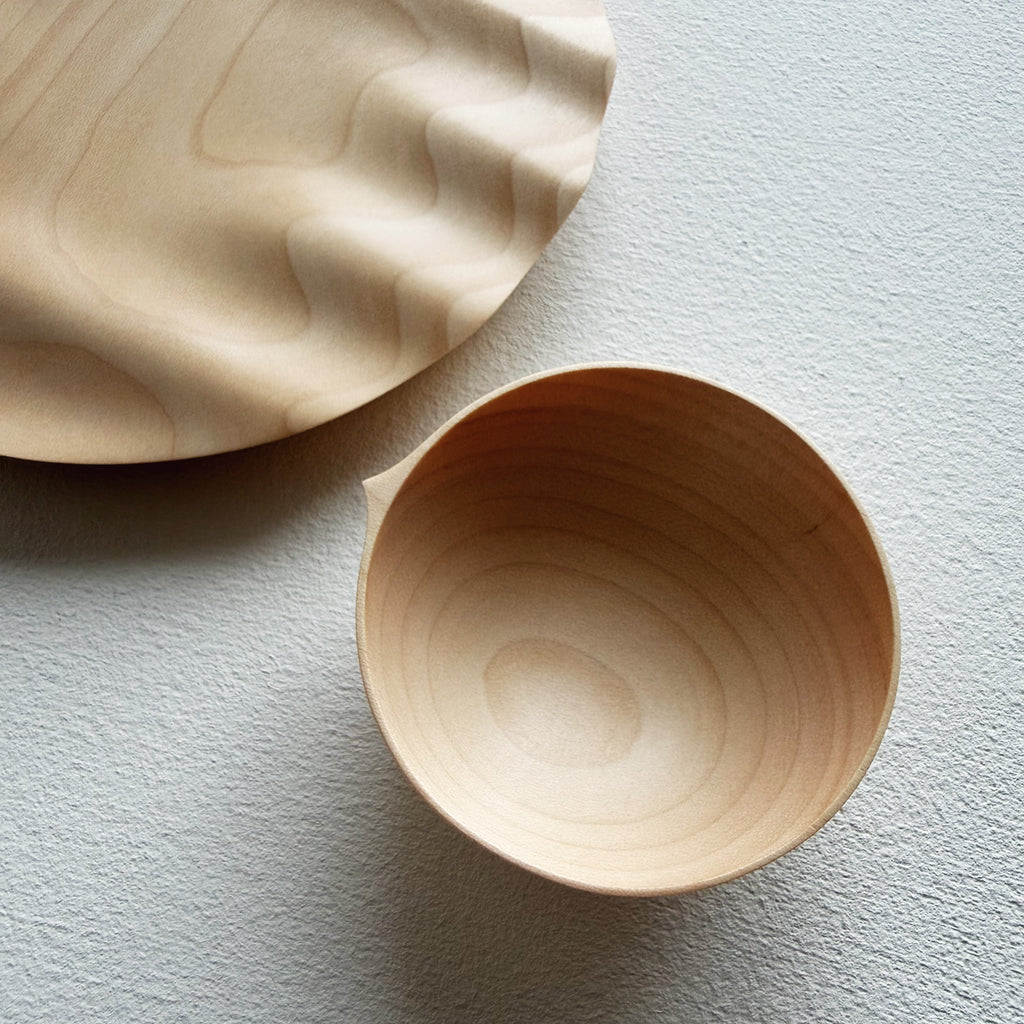 Close up of a sycamore bowl and detail of a sycamore wavy plate on a white background