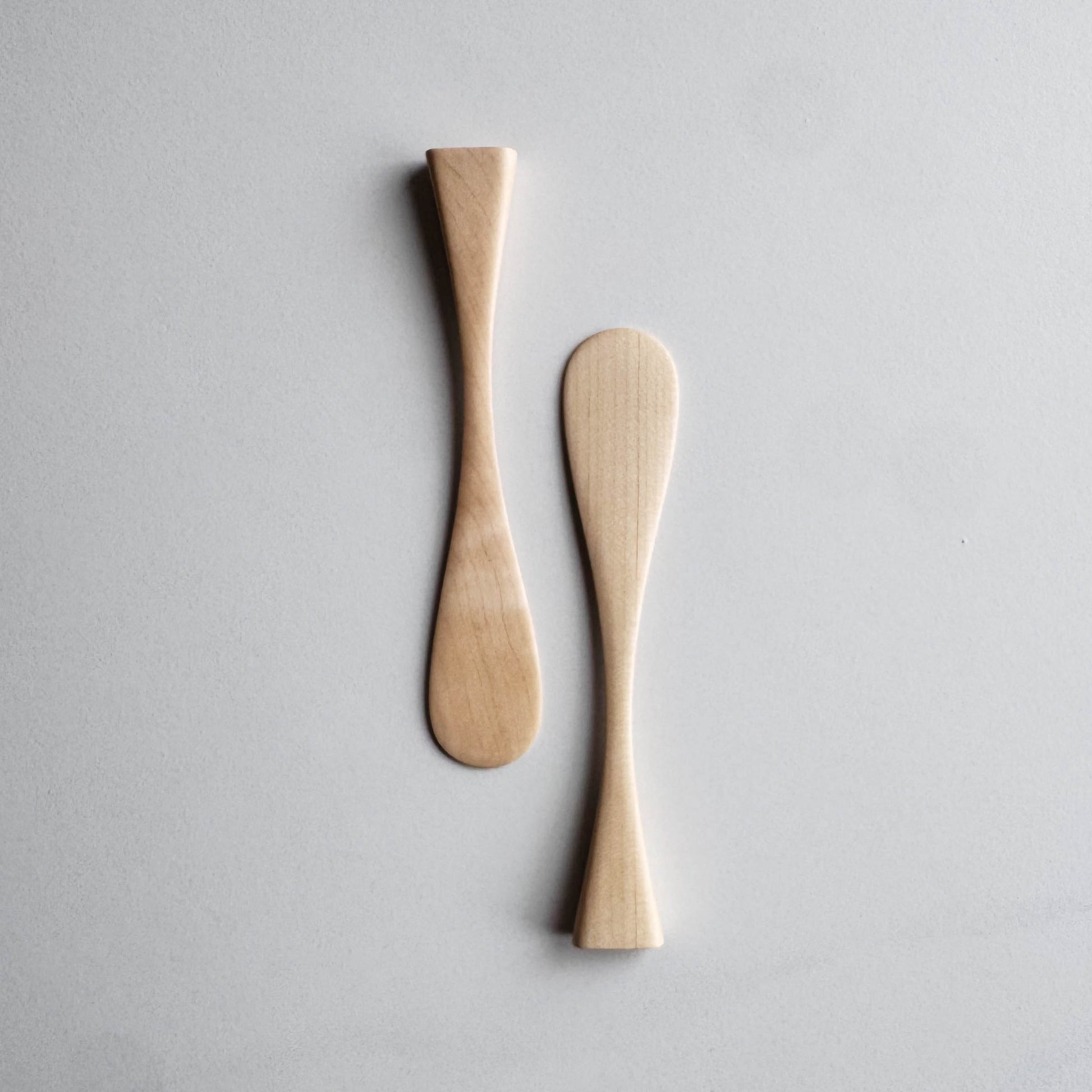 Two sycamore wood butter knives on a white background