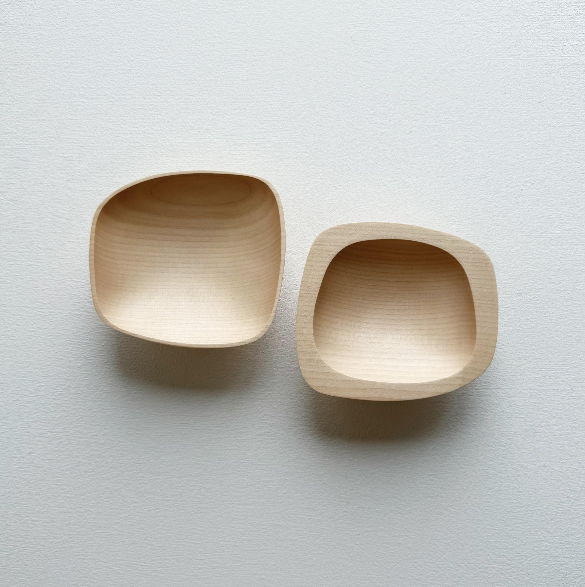 Two curved sycamore plinth bowls on a white background