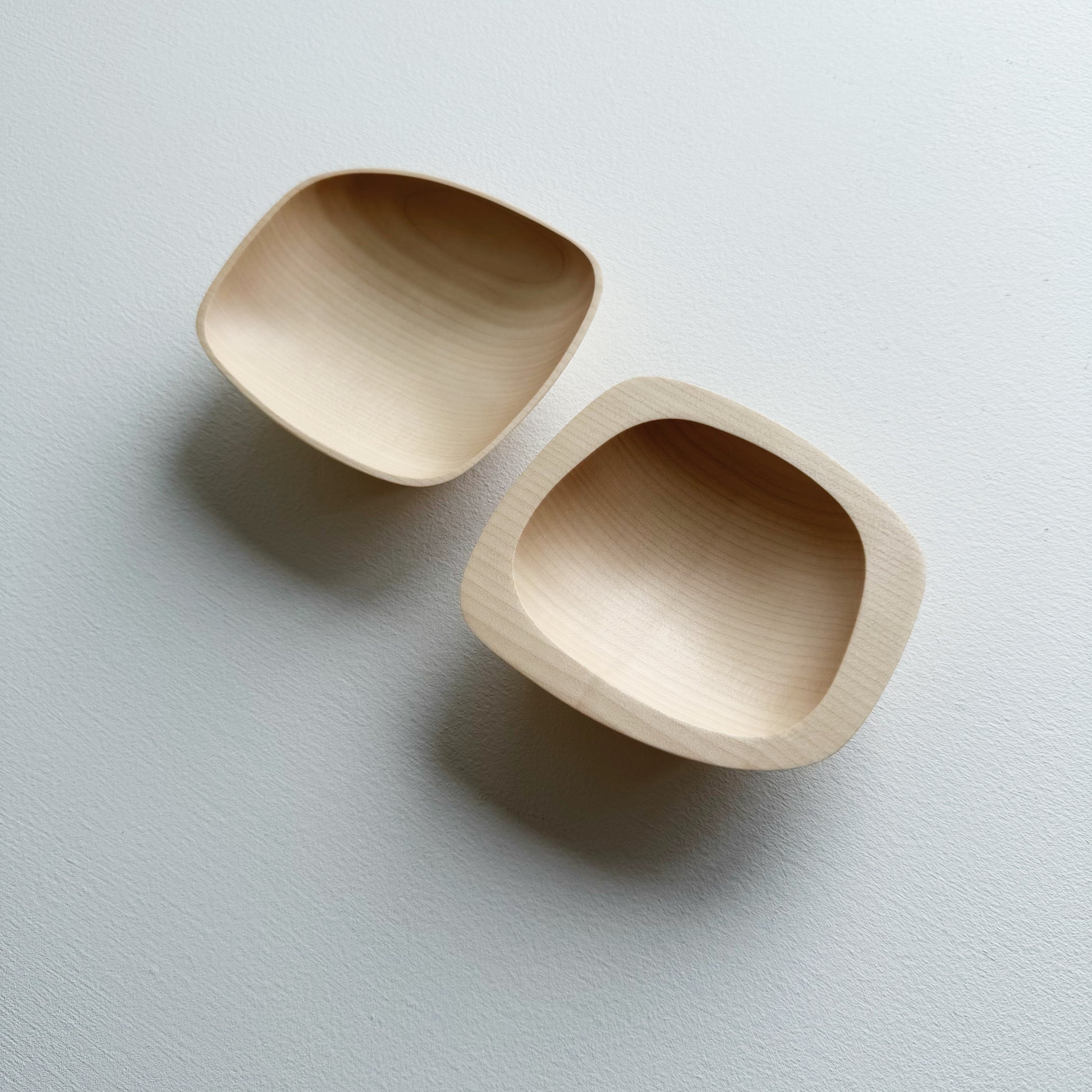 Two curved sycamore plinth bowls on a white background
