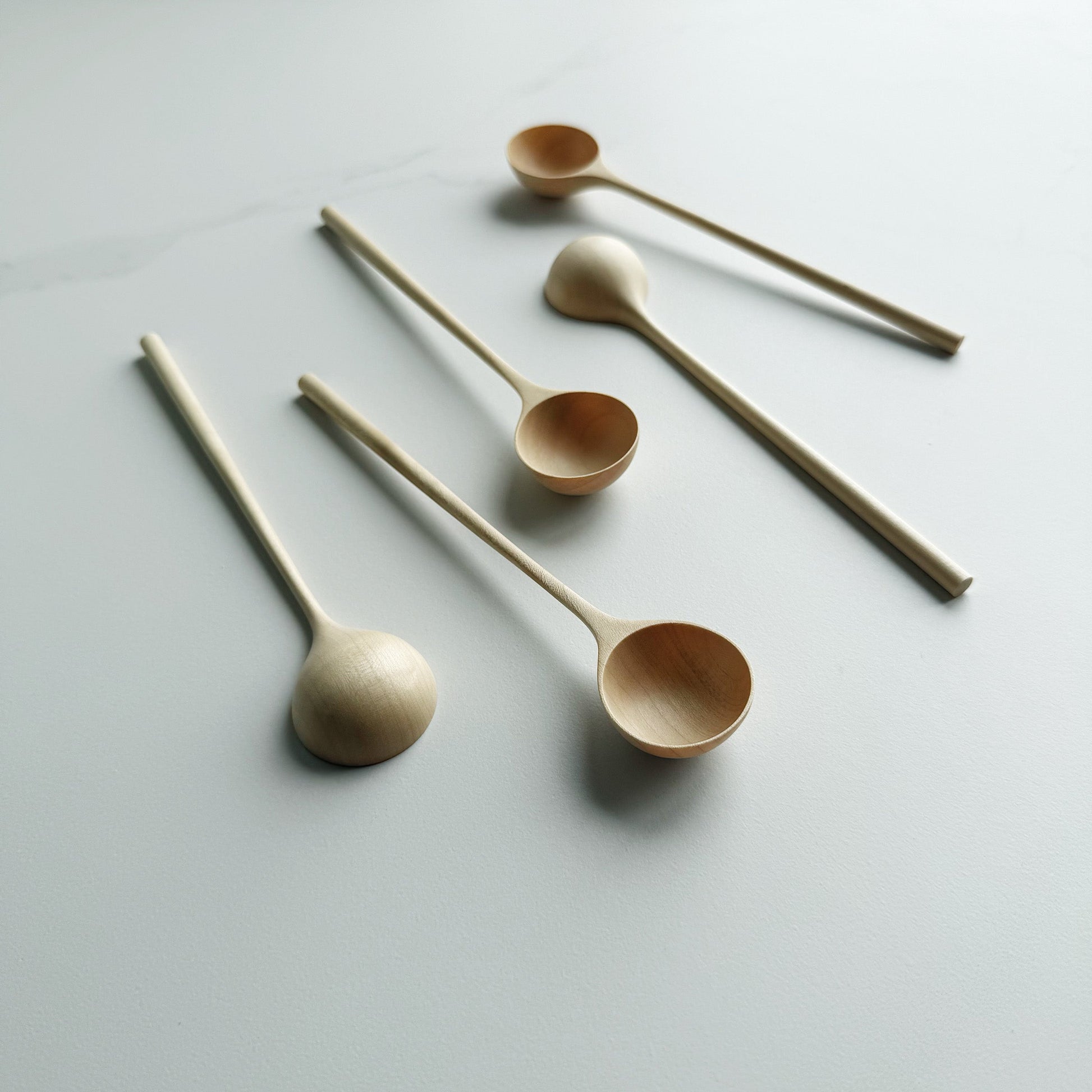 Set of five sycamore long stem spoons on a light background