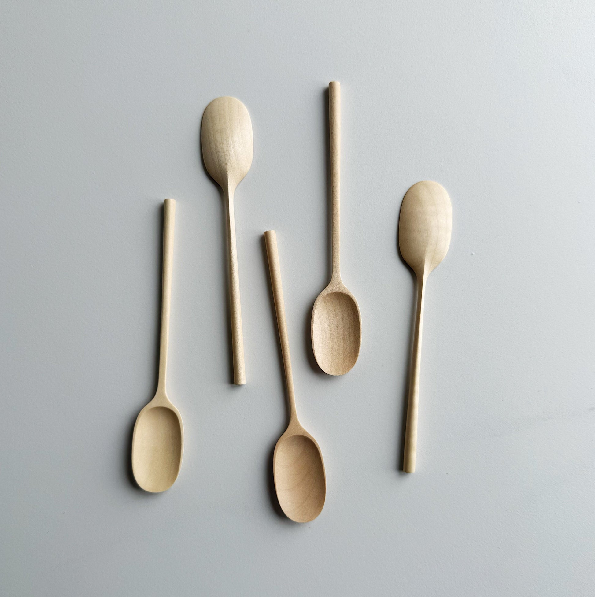 Set of five sycamore small paddle spoons on a light background
