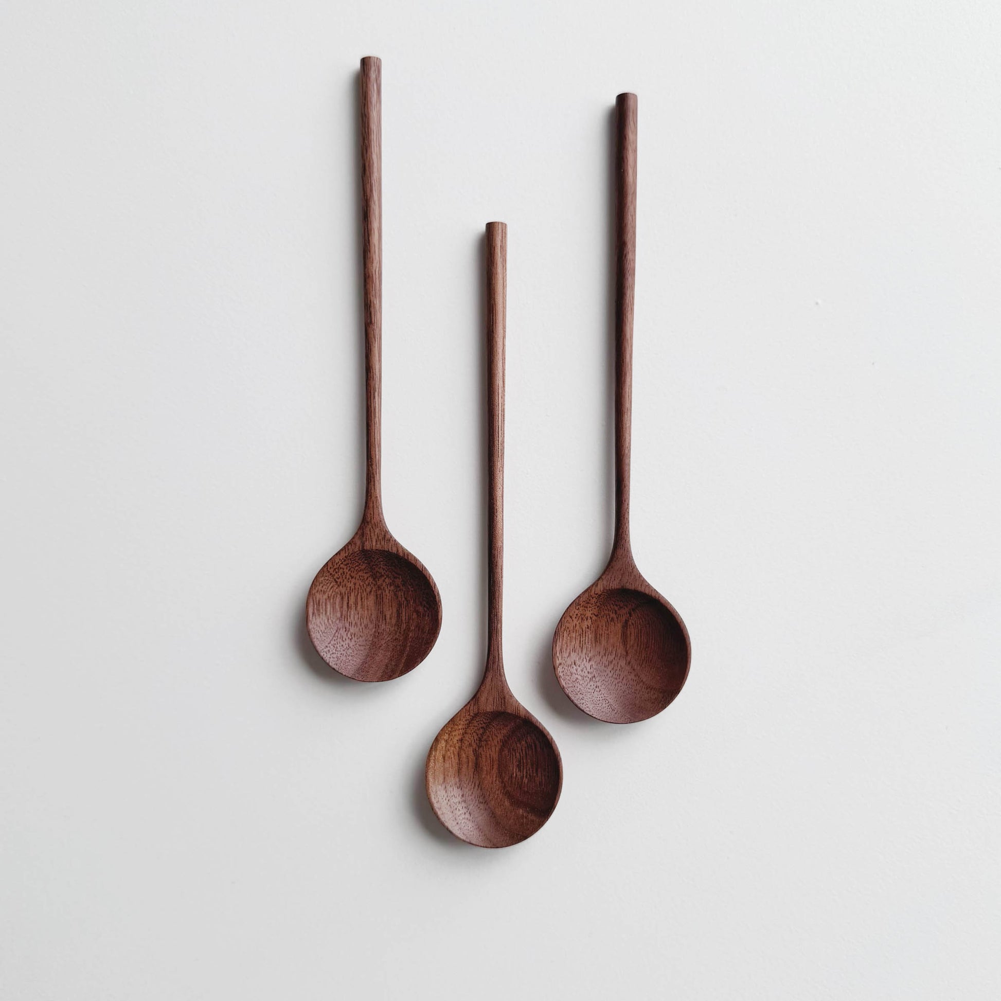 Three walnut wooden spoons on a white background