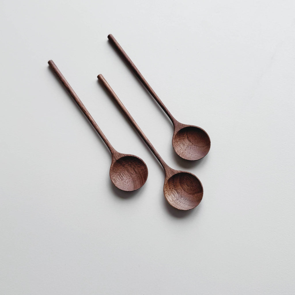 Three walnut wooden spoons on a white background
