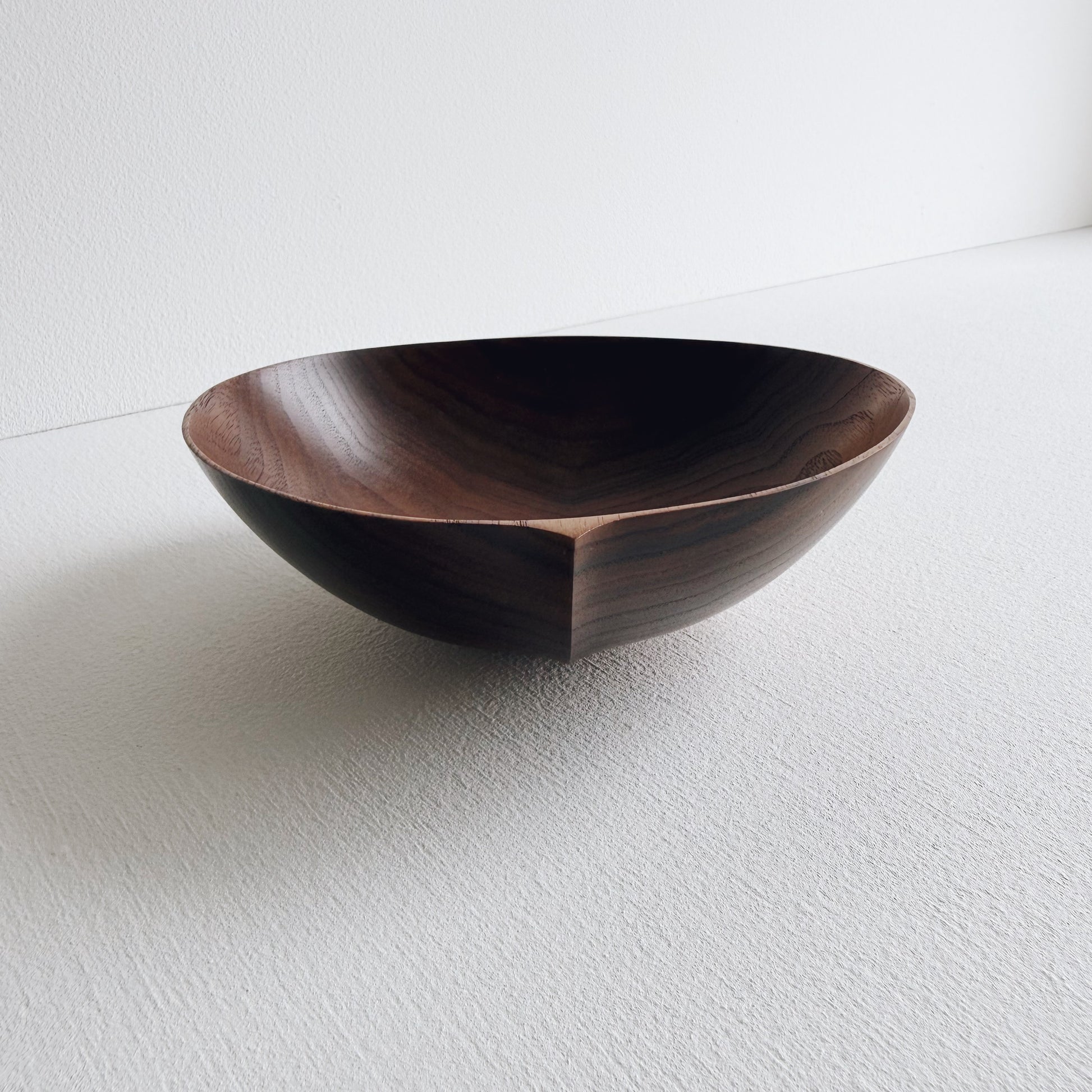 Walnut wood bowl on a light gray background