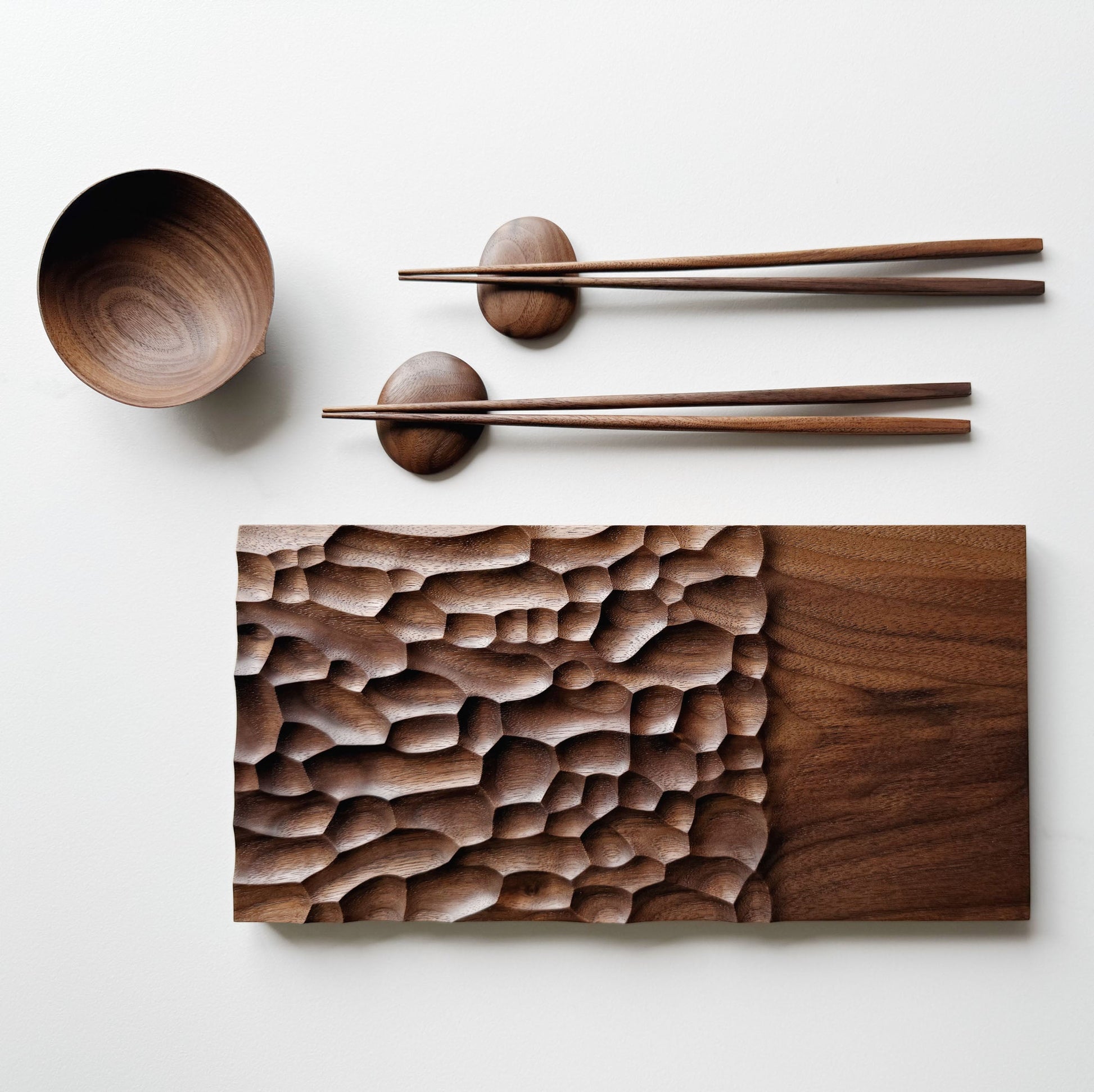 Wide presentation board with crater design in walnut, with a bowl, wooden chopsticks & pebble rests.
