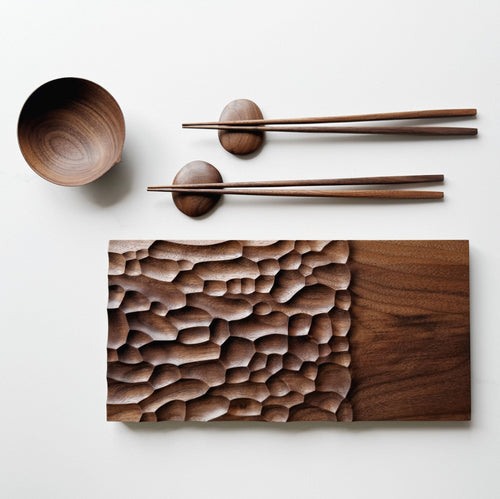 Wide presentation board with crater design in walnut, with a bowl, wooden chopsticks & pebble rests.

