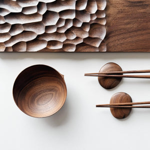 Wide presentation board with crater design in walnut, with a bowl, wooden chopsticks & pebble rests.
