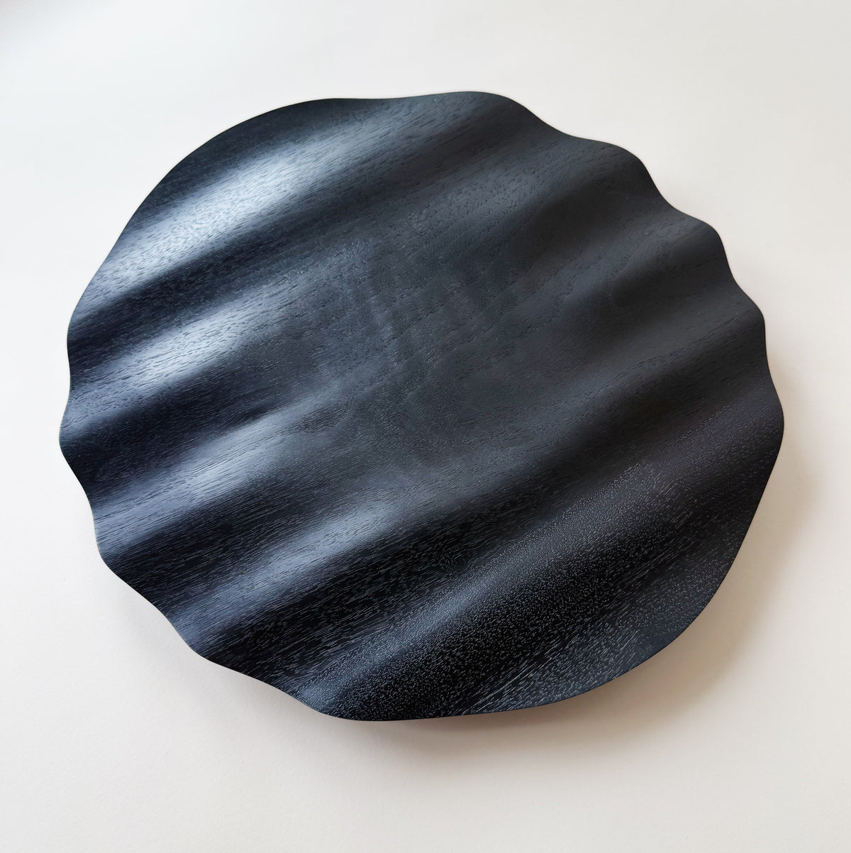Wavy charger plate in ebonised walnut